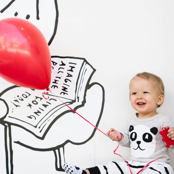 Smiling toddler holding red balloon string