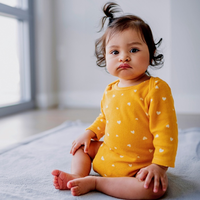Baby sitting calmly in yellow onesie