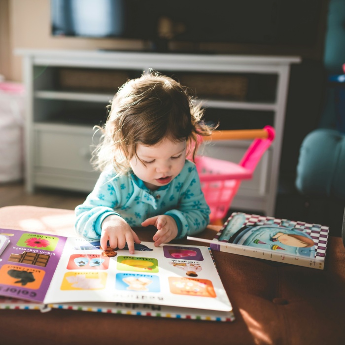 Curious toddler pointing at a book.