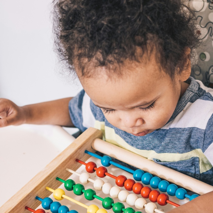 Child focused on colorful wooden abacus