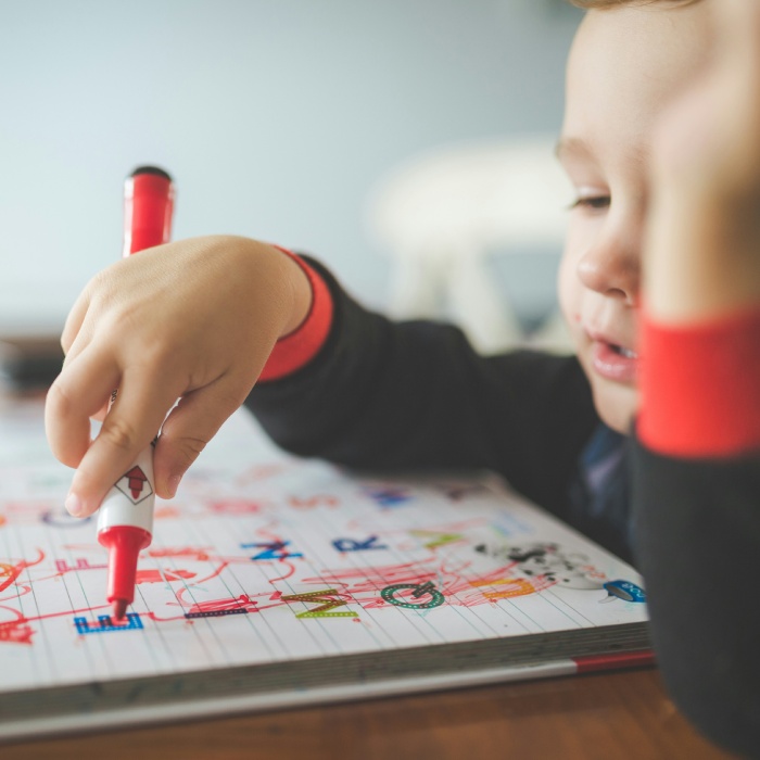 Child concentrating while coloring with marker.